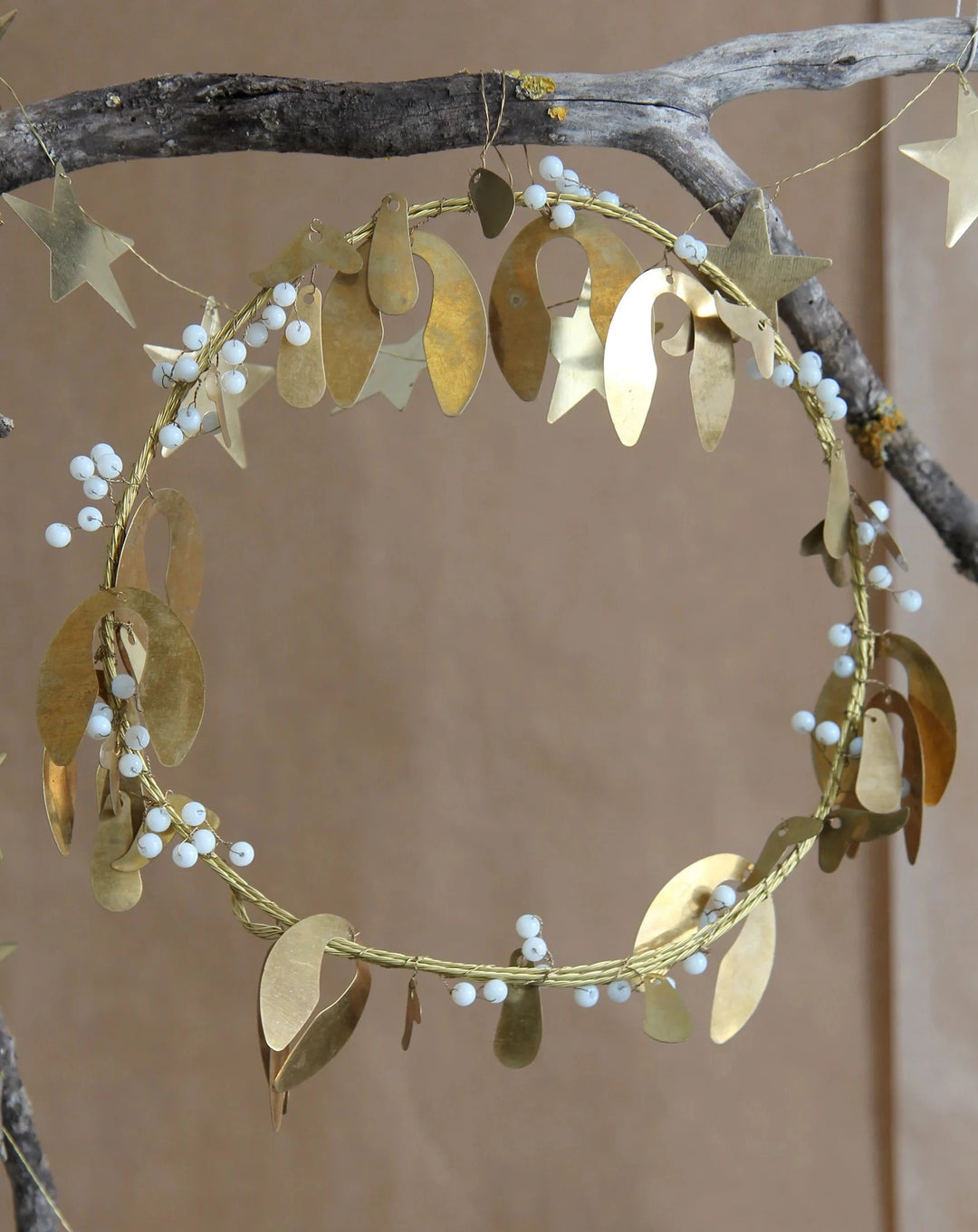 brass mistletoe and wire wreath with white beads hanging on branch