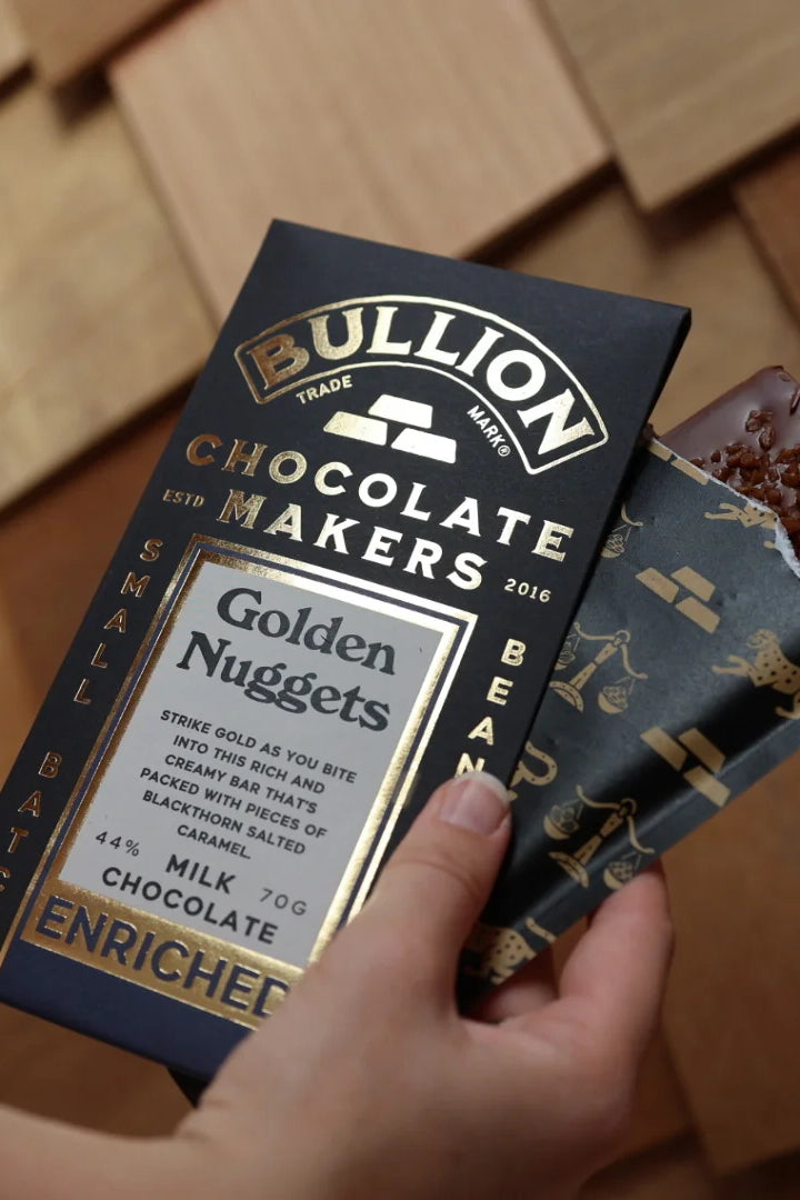 Bullion Chocolate Makers Golden Nuggets chocolate bar packaging held by a hand.