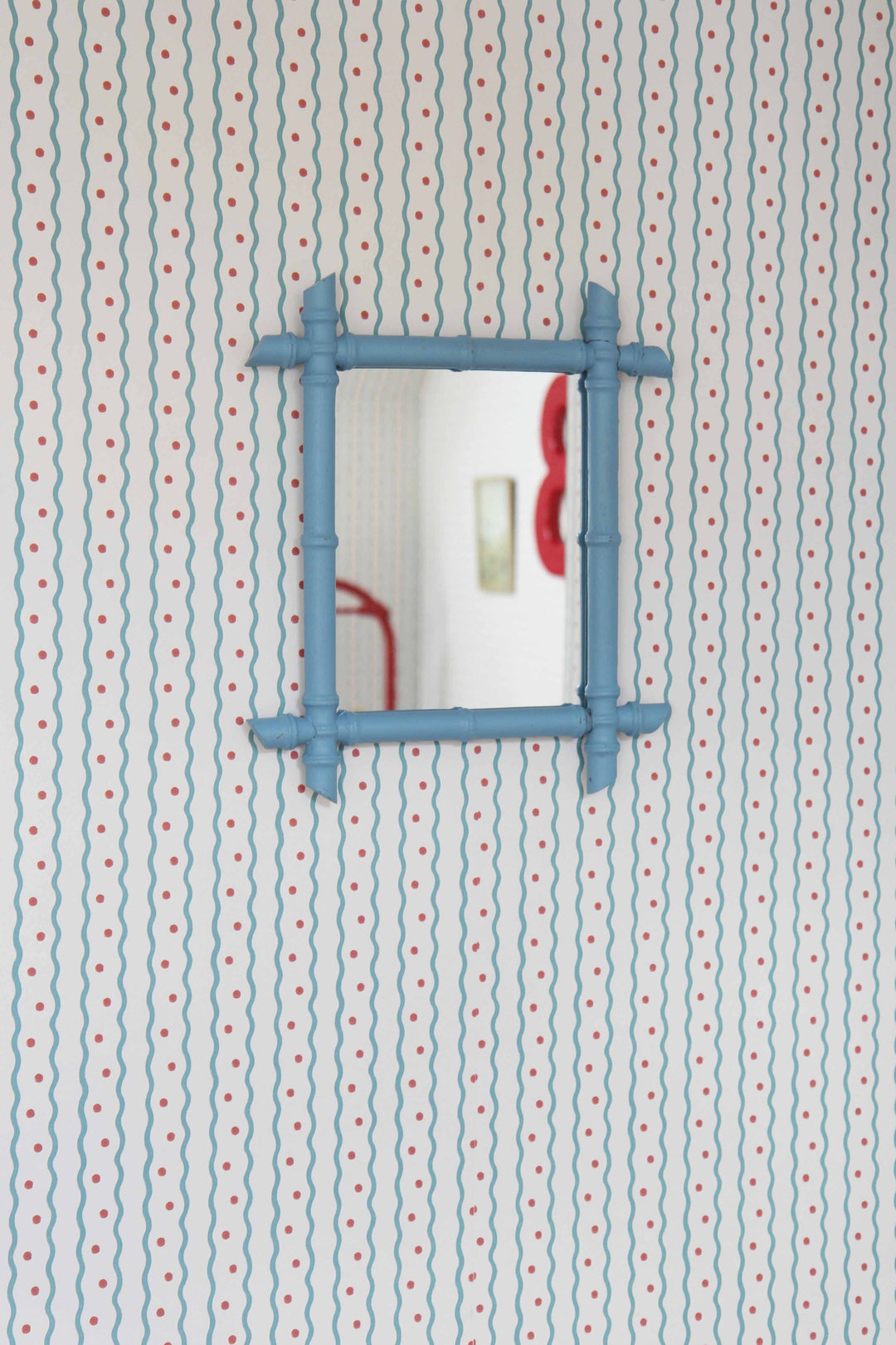 Honfleur wallpaper in cornflower wavy stripe with red spots pictured with faux blue bamboo blue mirror 