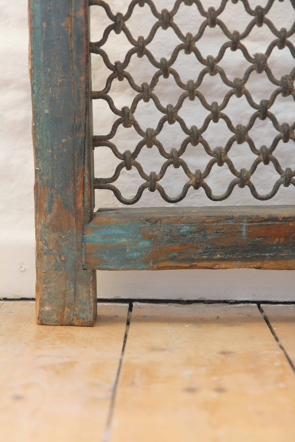 Decorative metal screen with lattice design on a wooden frame against a light background