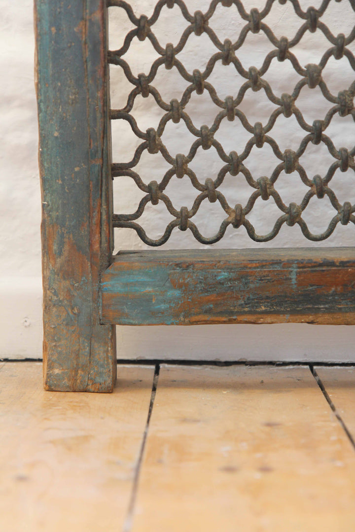 Decorative metal screen with lattice design on a wooden frame against a light background