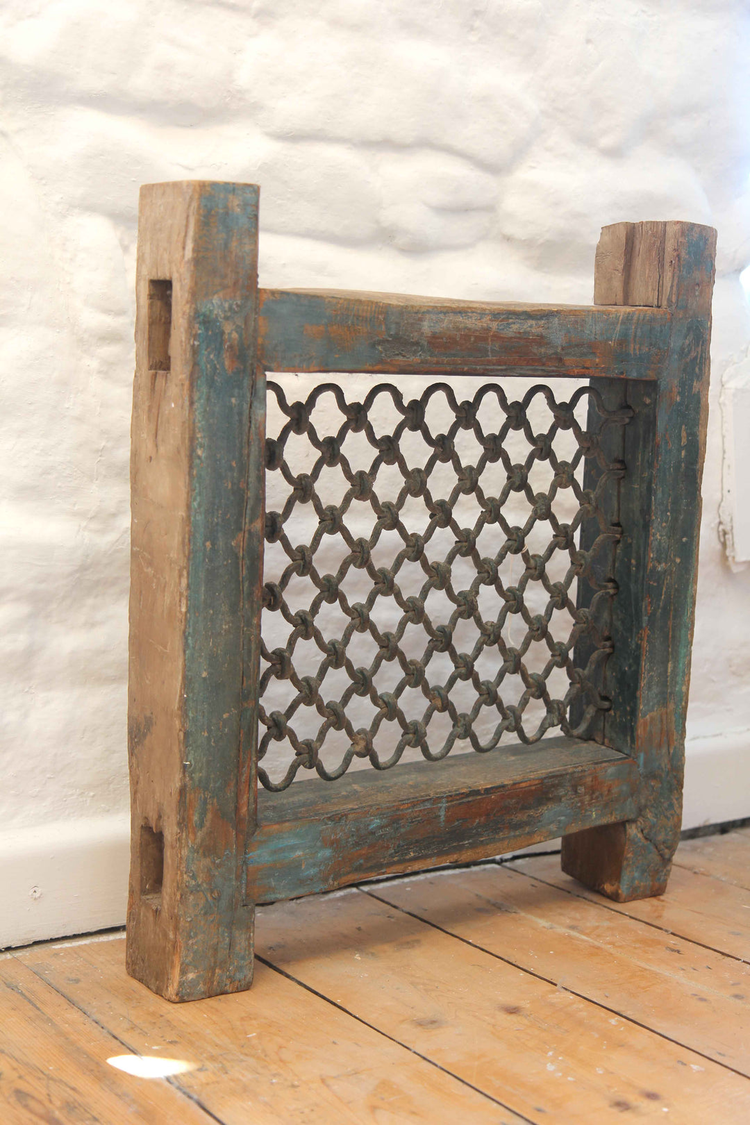 Wooden radiator cover with decorative lattice design on a wooden floor.