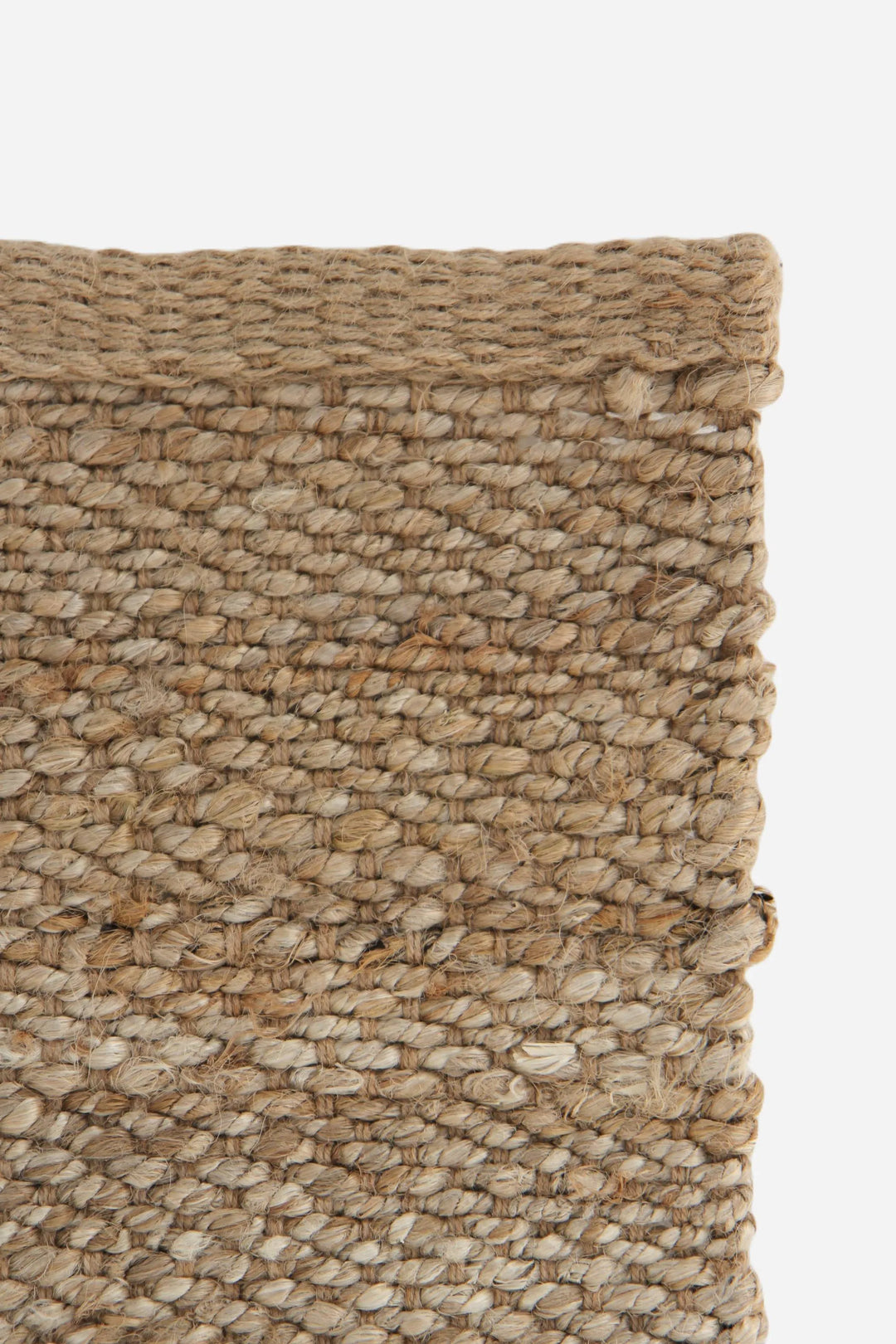 Close-up of a textured woven rug with natural colors on a white background