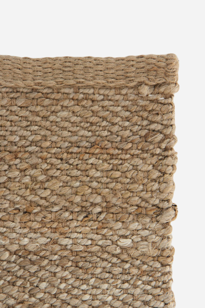 Close-up of a textured woven rug with natural colors on a white background