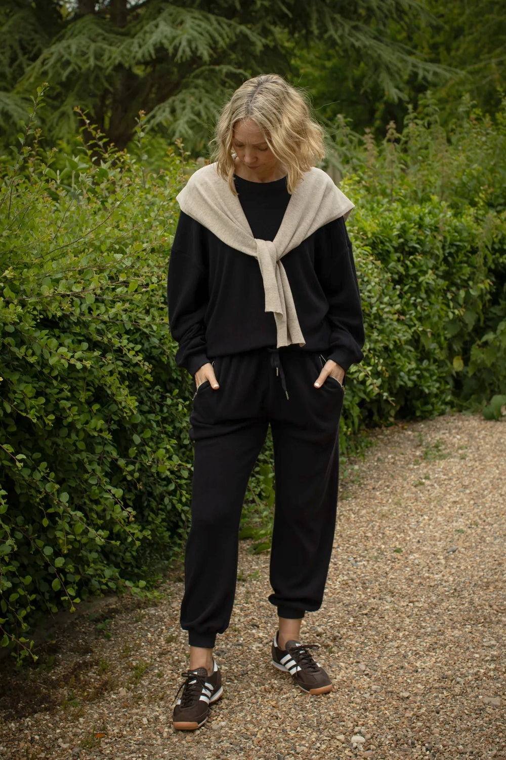 Person wearing a navy sweatshirt with a beige scarf in a garden setting