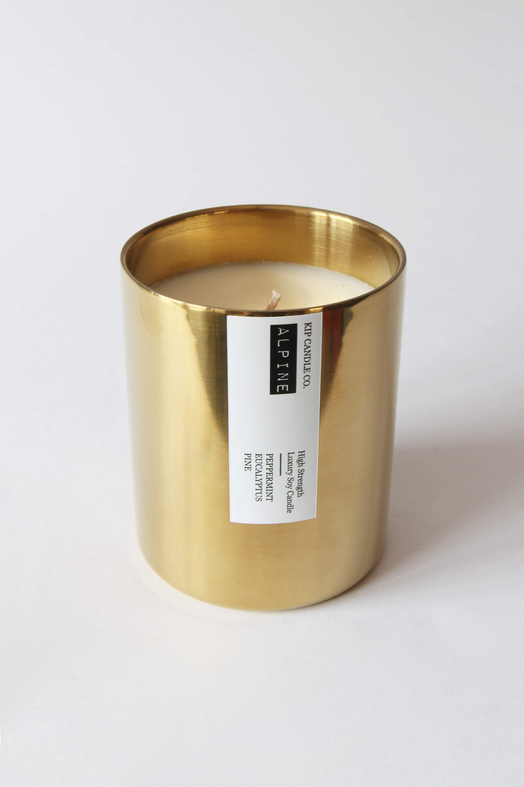 Gold candle holder with a white candle inside on a white background