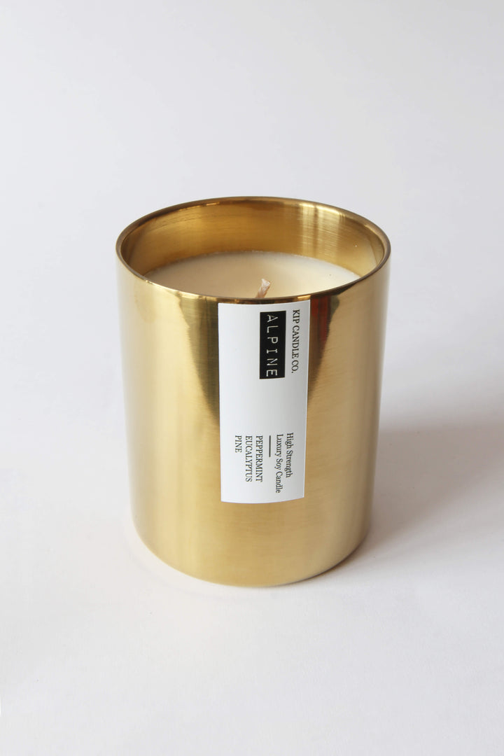Gold candle holder with a white candle inside on a white background