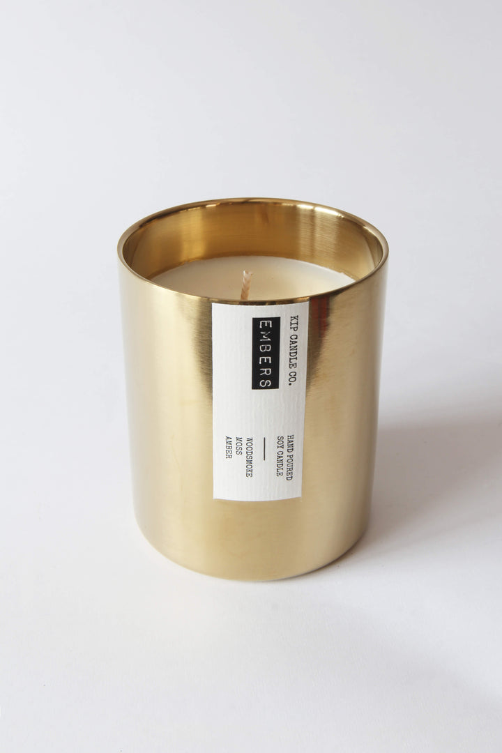 Candle in a gold holder with a label on a white background