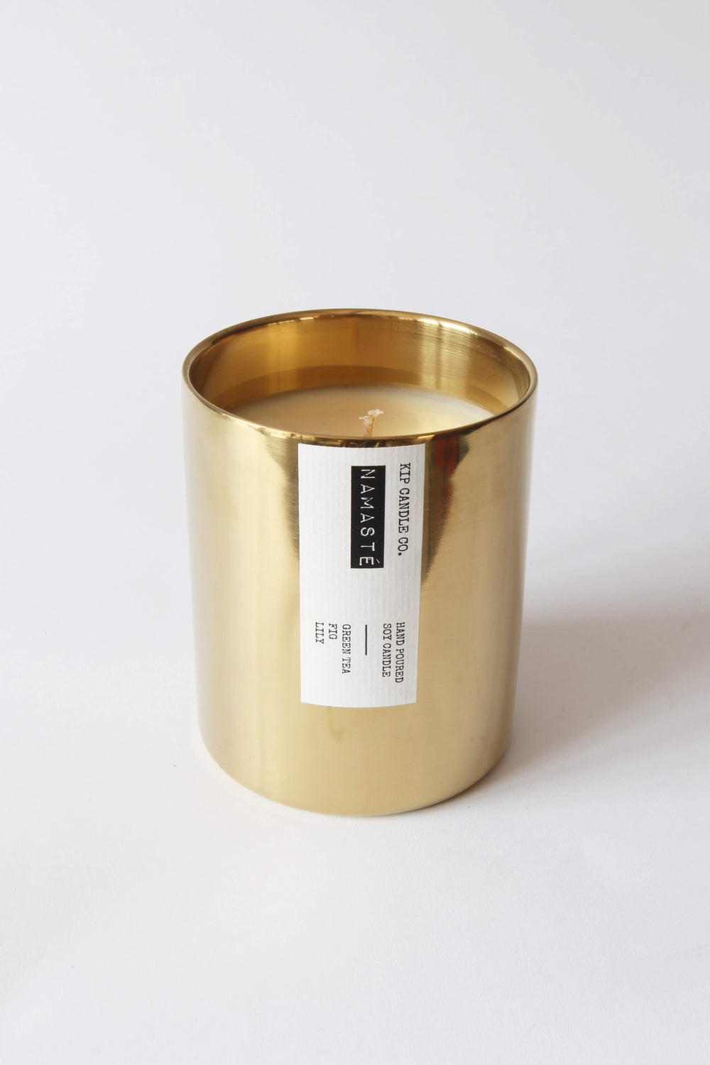 Gold candle holder with a white candle inside on a white background