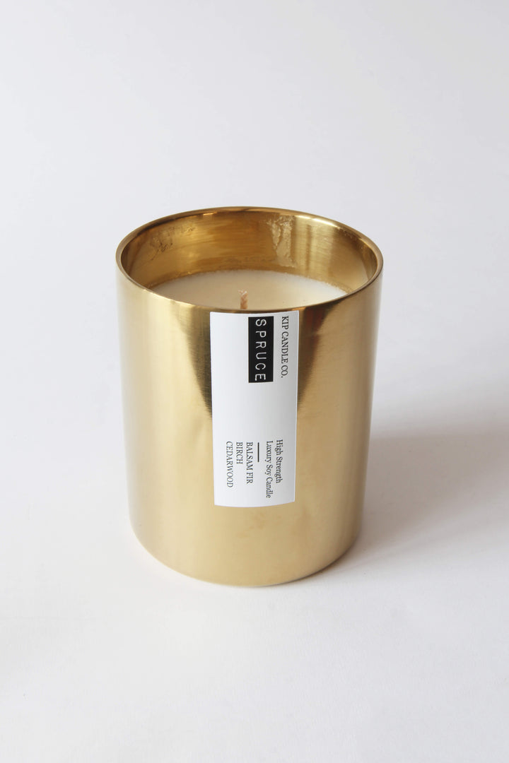 Gold candle holder with a white candle inside on a white background