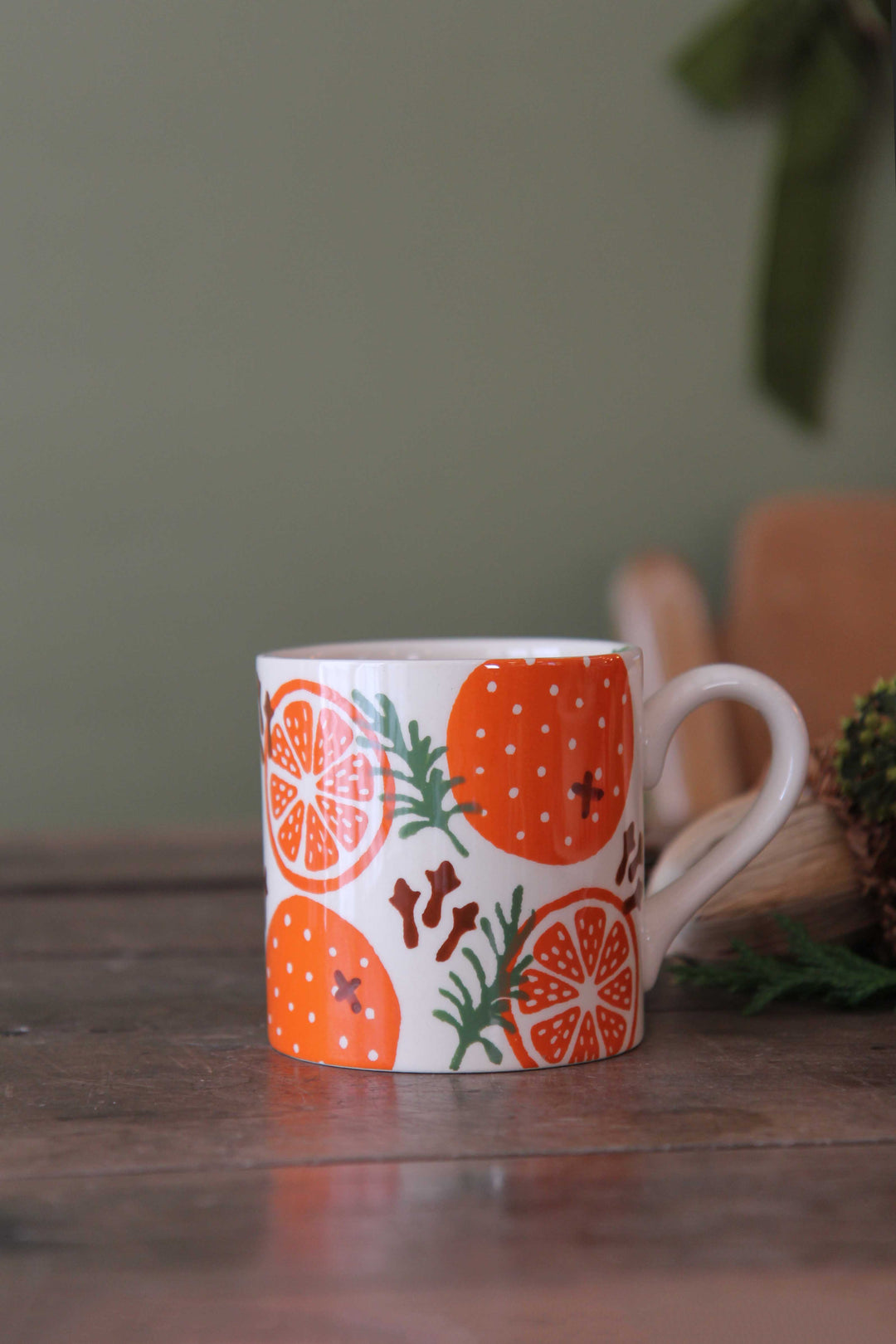 Mug with orange and leaf pattern on a wooden surface