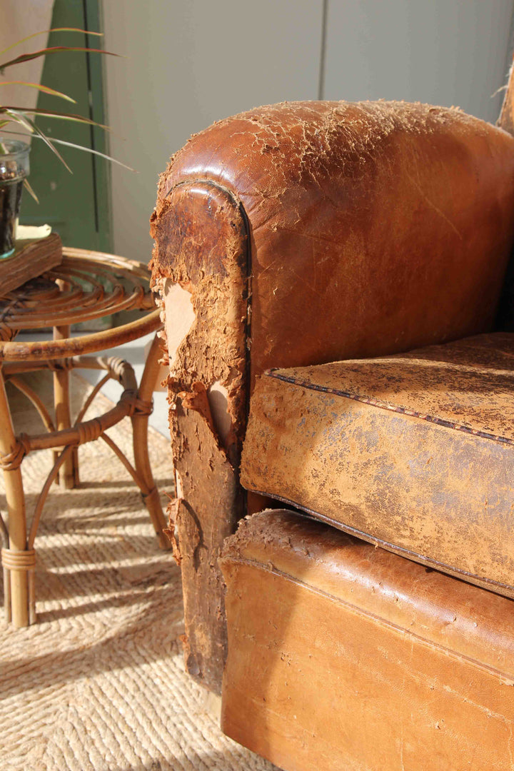 Brown leather armchair with visible wear and tear in a room setting.