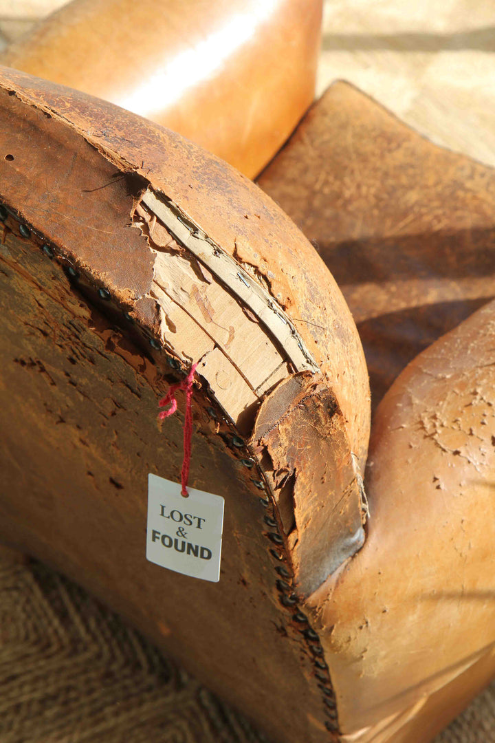 Brown leather item with a 'Lost & Found' tag on a textured surface