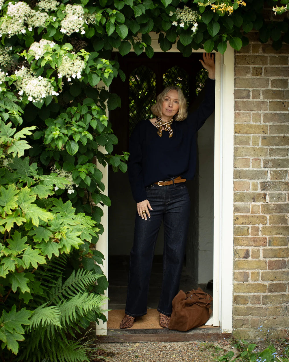 Person standing in a doorway with greenery and flowers around