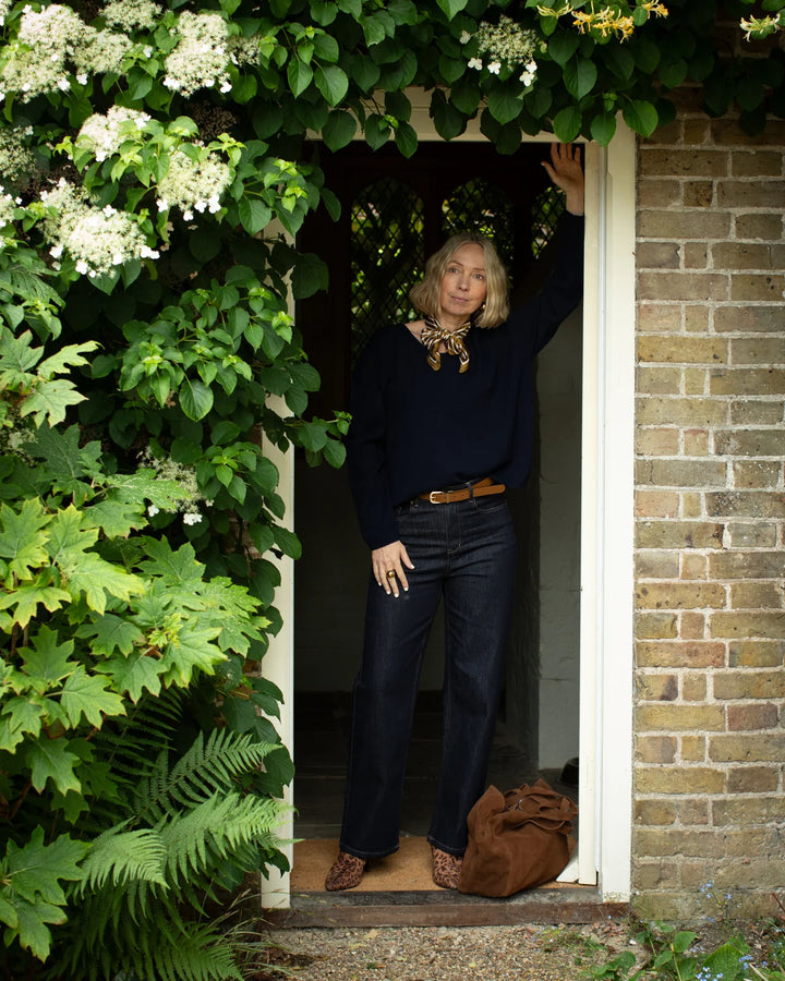 Person standing in a doorway with greenery and flowers around