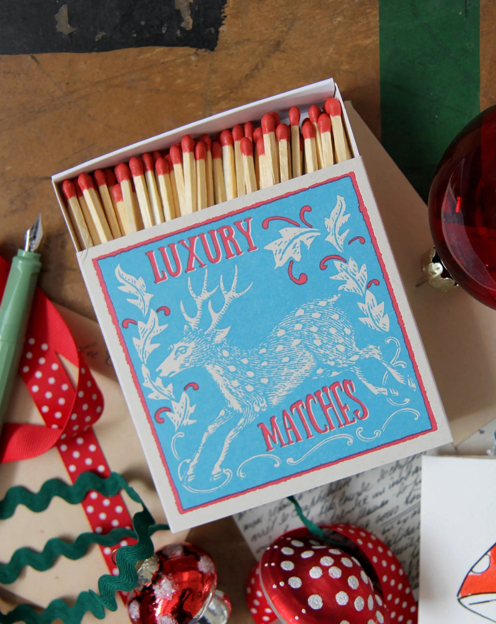 luxury matches with vintage stag design surrounded by Christmas decorations, ribbons and trims