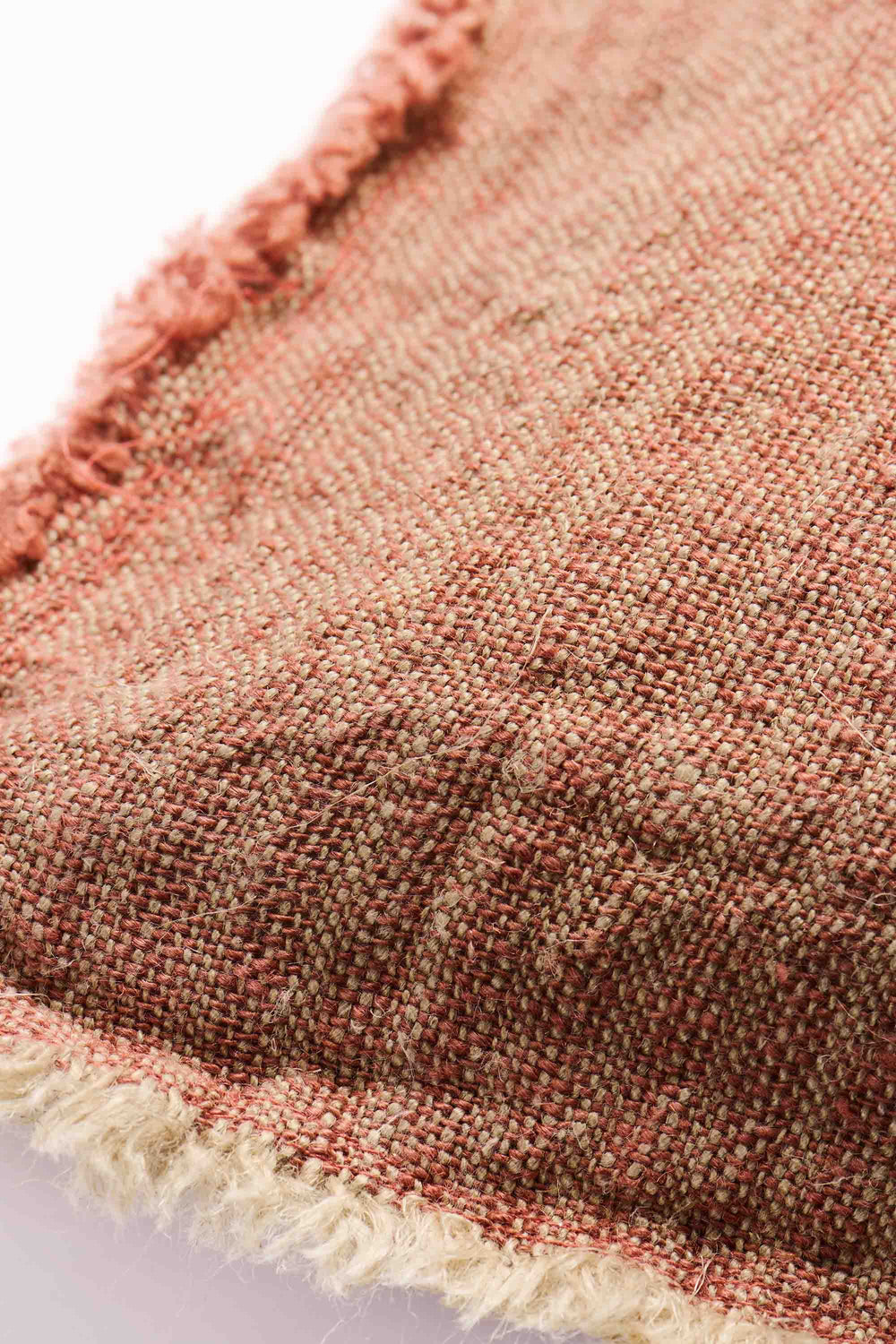 Close-up of a textured rust/pink fabric with frayed edges on a white background