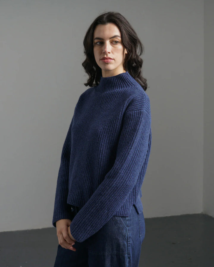Person wearing a blue sweater against a plain background