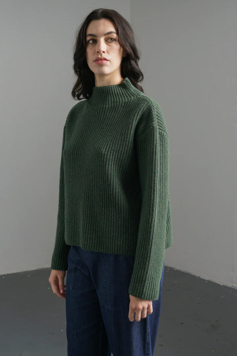 Woman wearing a green sweater against a plain background