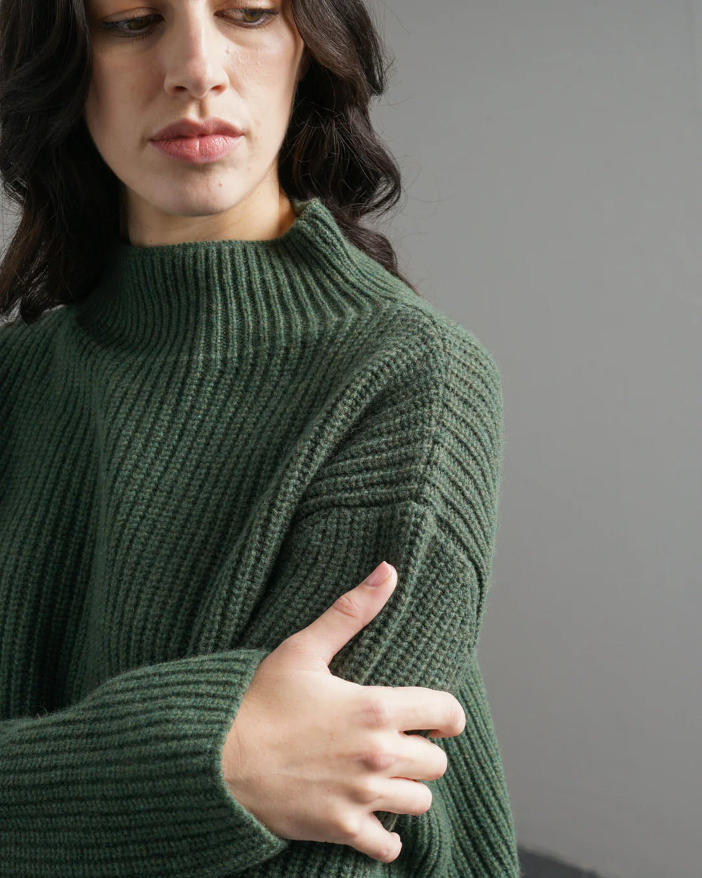 Person wearing a green sweater against a gray background
