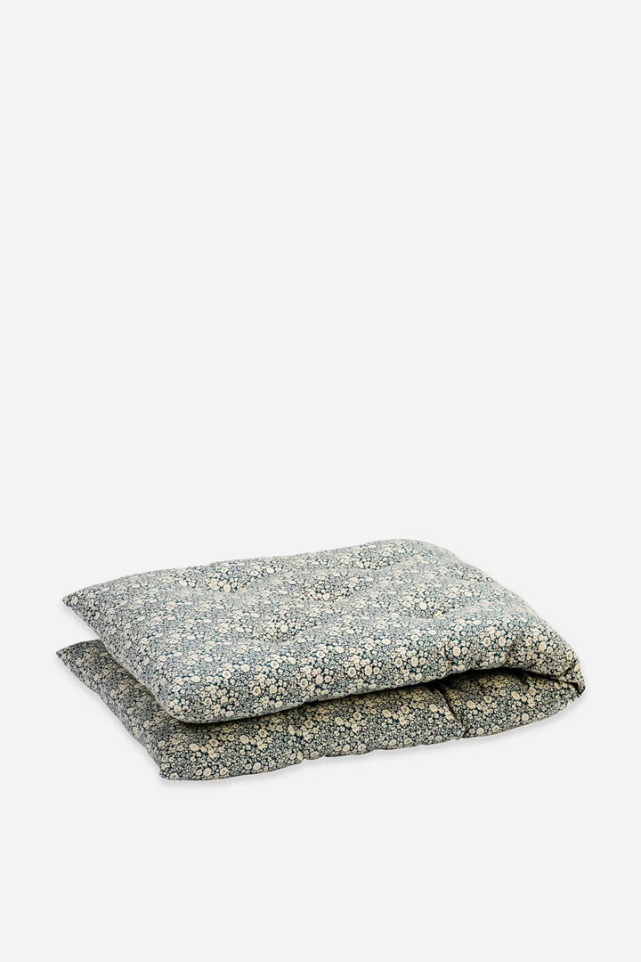 A folded outdoor mattress with a floral blue, white, and beige pattern, shown on a plain light gray background.