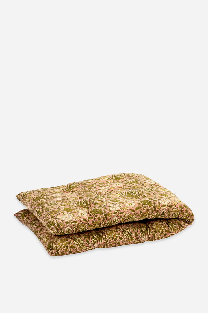 A folded quilted mattress topper with a textured, floral-like pattern in olive green, tan, and beige, set against a plain light gray background.