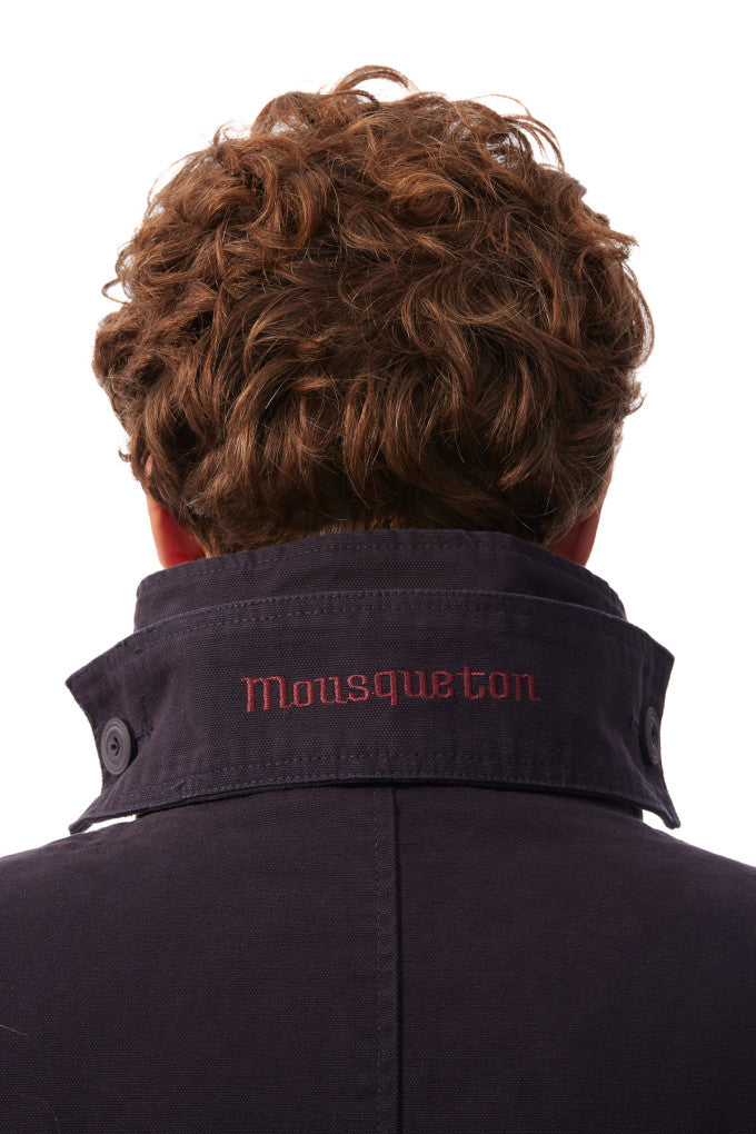 Person wearing a dark jacket with 'Mousqueton' branding on a white background