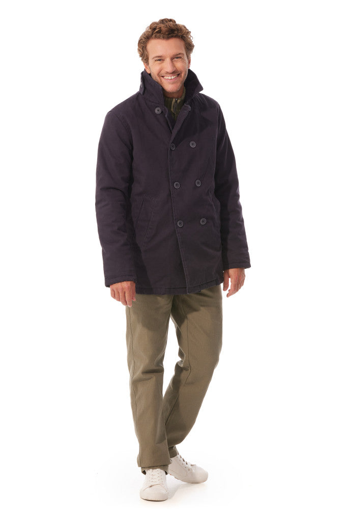 Man wearing a dark coat and light-colored pants on a white background