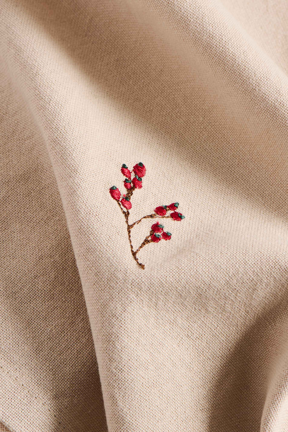 Embroidered red floral design on beige fabric