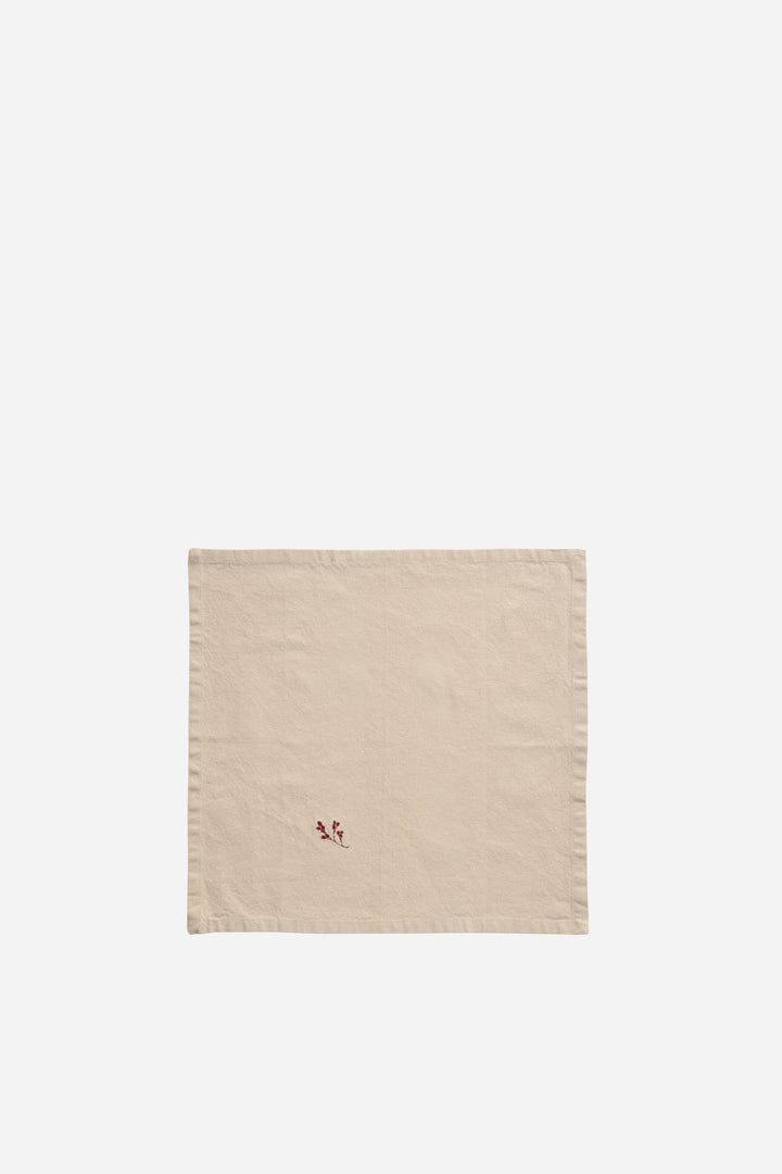 Beige woven rug with a red winterberry motif on a white background