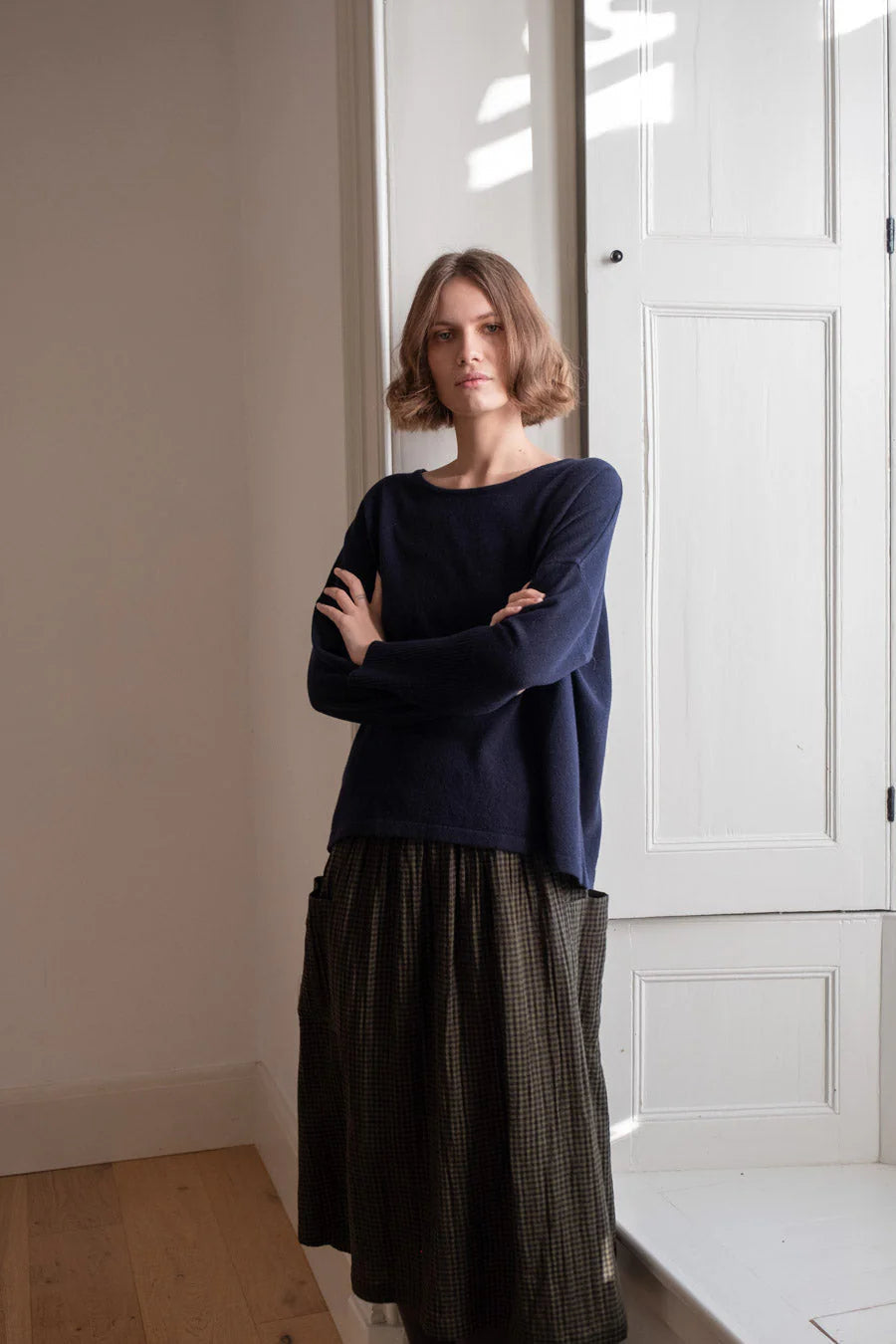 Woman standing in a room with white walls and a large window