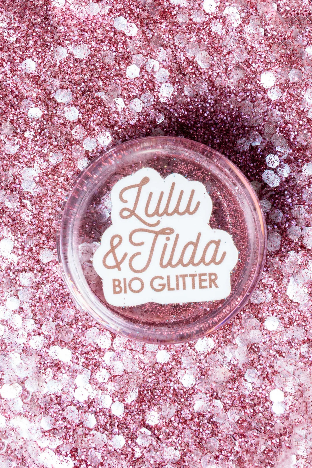 Bowl of pink glitter with 'Lulu & Tilda Bio Glitter' label on a pink glitter background