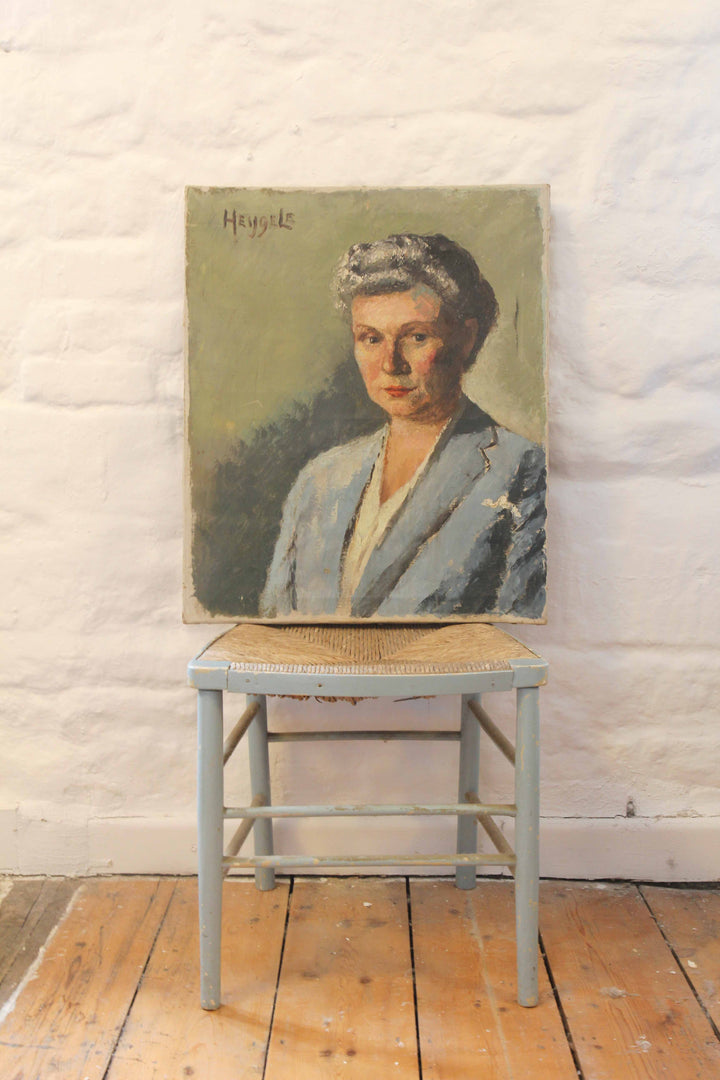 Portrait of a woman on a wooden stool against a white brick wall.