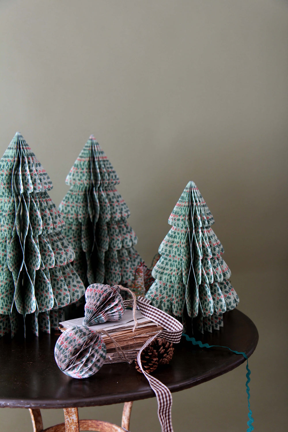 Knitted Christmas trees on a wooden table against a plain wall