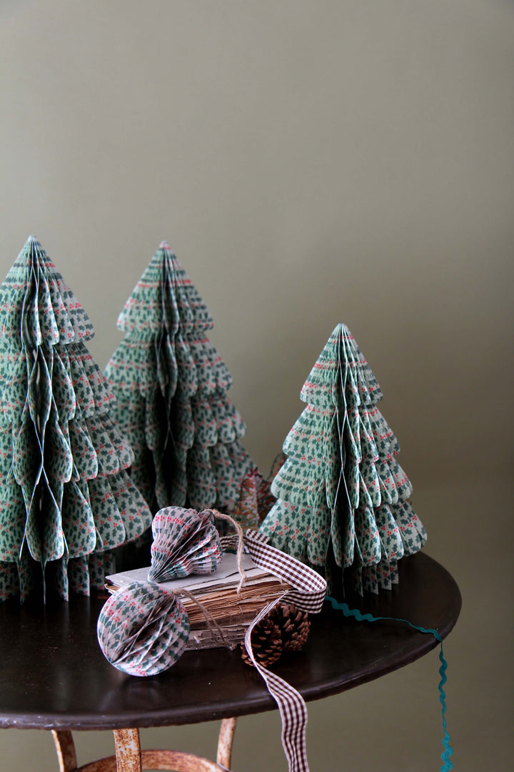 Knitted Christmas trees on a wooden table against a plain wall