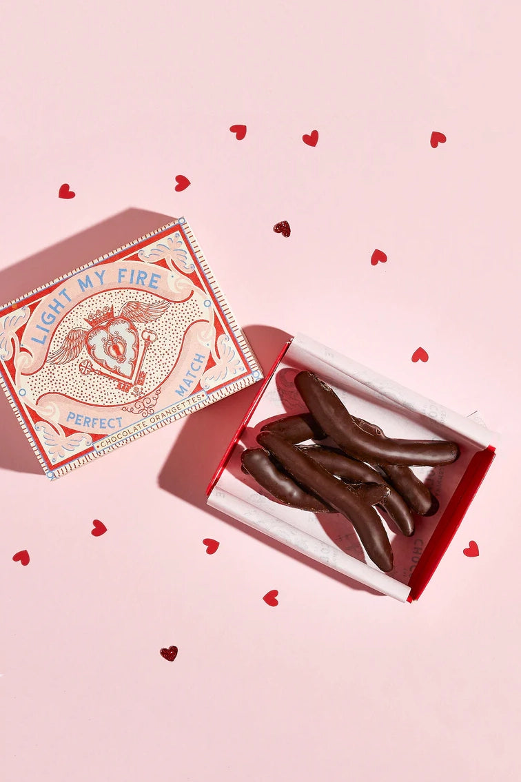 Chocolate hearts in a decorative box on a pink background with heart shapes.