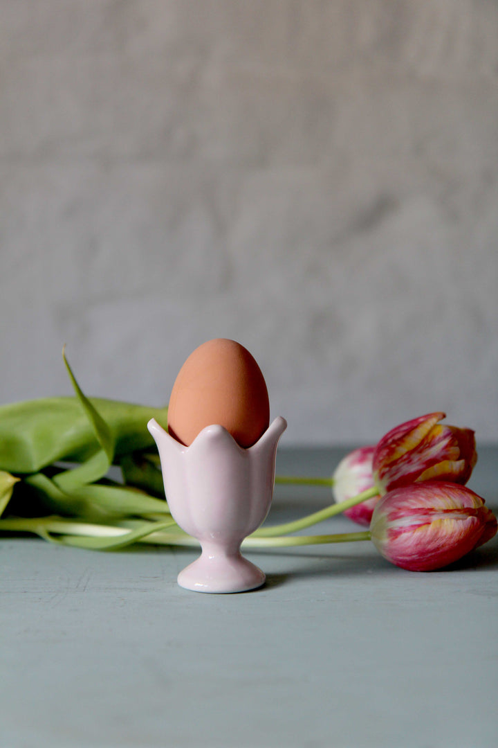 tulip shaped egg cup in pink with boiled egg and pink tulips in background