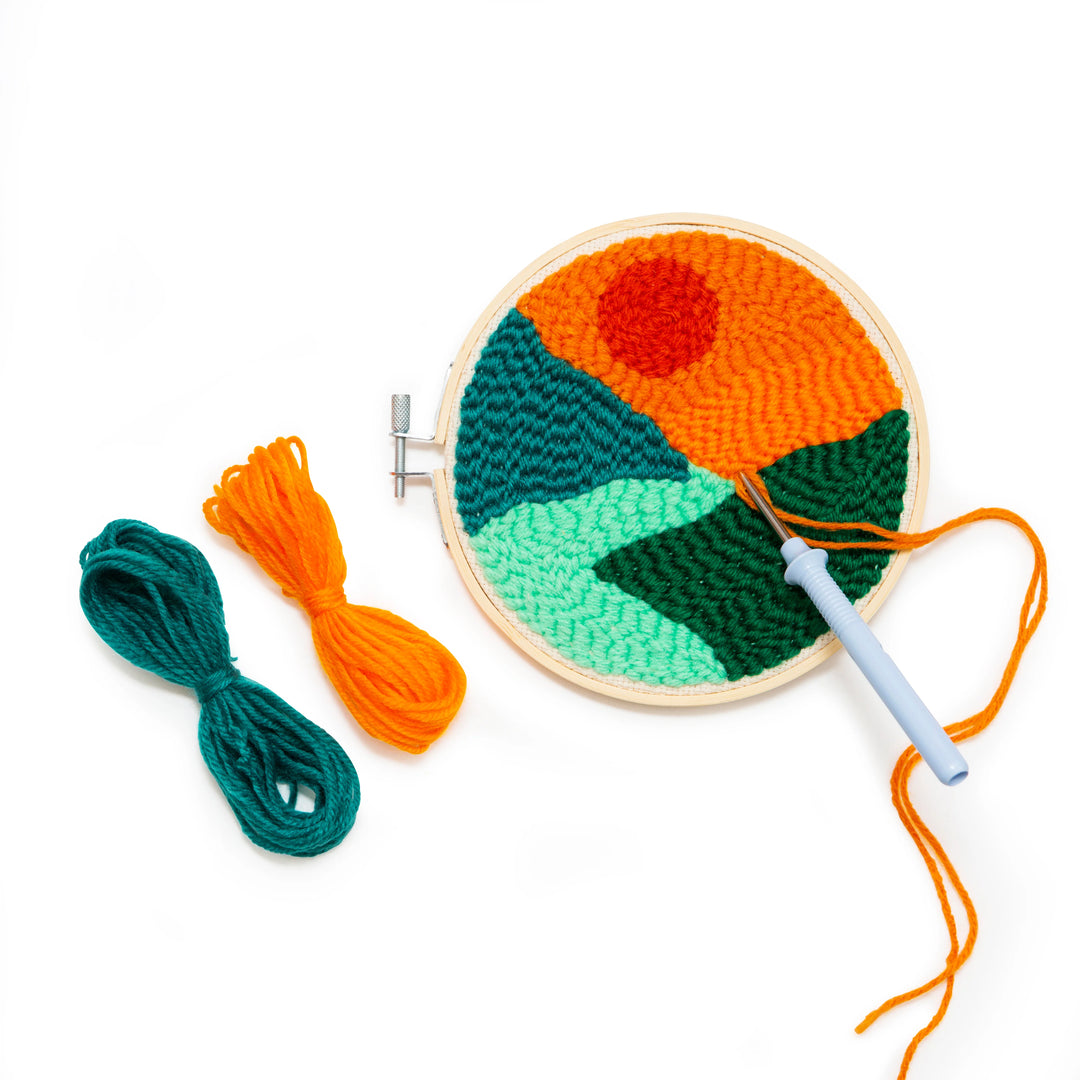 Embroidery hoop with colorful knitted design and yarn on a white background