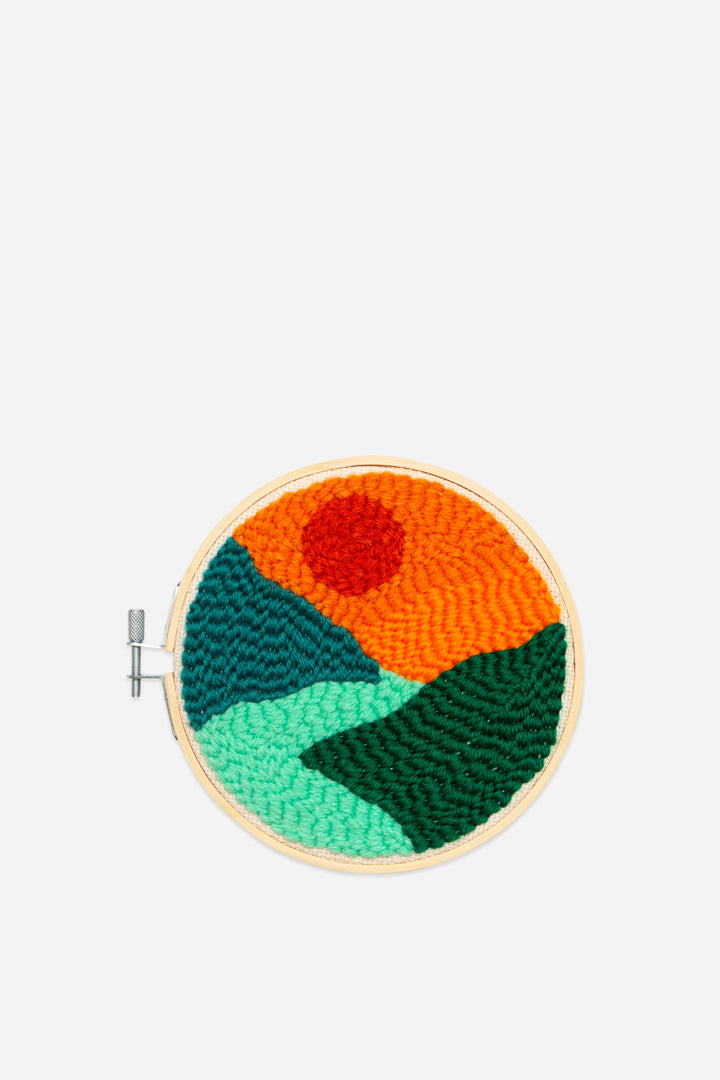 Embroidery hoop with a colorful landscape design on a white background