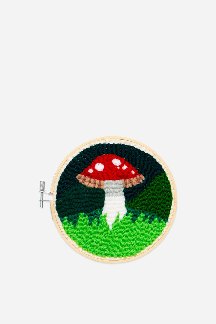 Embroidery hoop with a red and white mushroom design on a green background