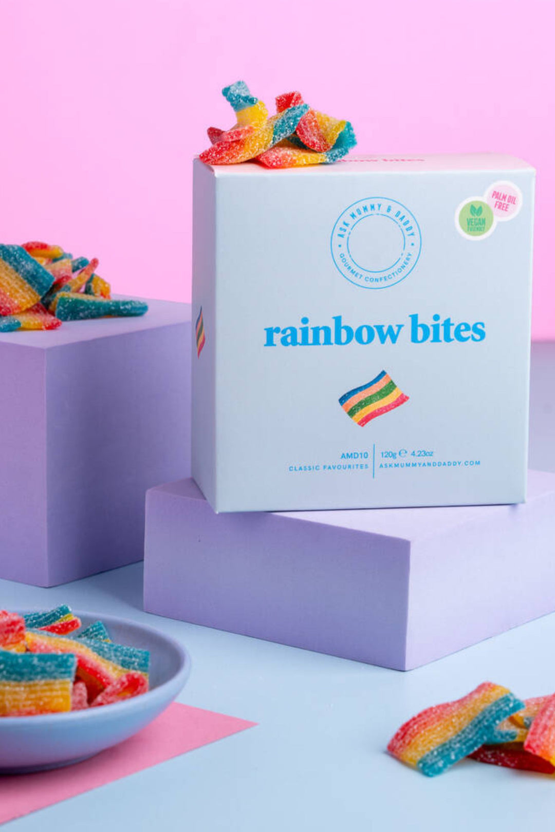 Box of rainbow bites candy with colorful gummy candies on a pastel background