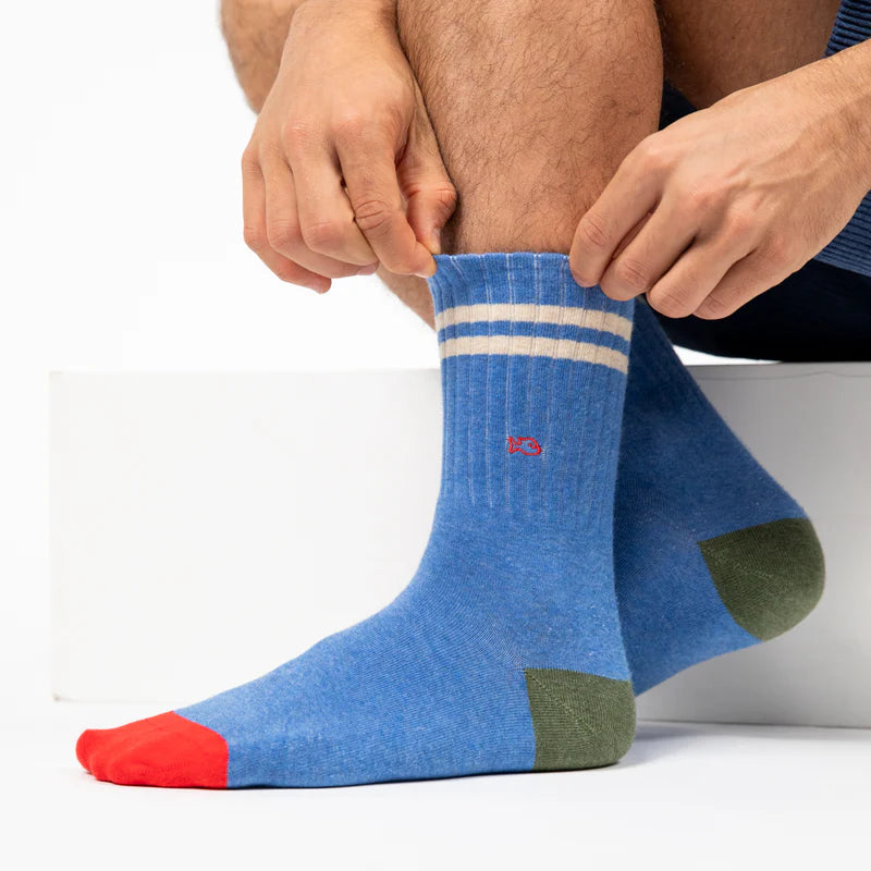 Person wearing blue socks with white stripes and red accents on a white background