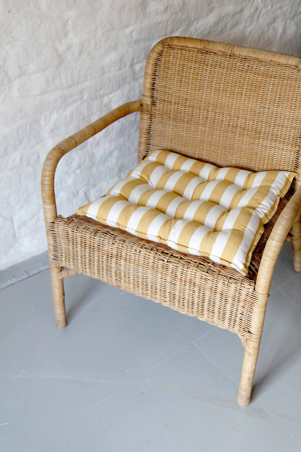 yellow and white striped cotton seat cushion on rattan chair