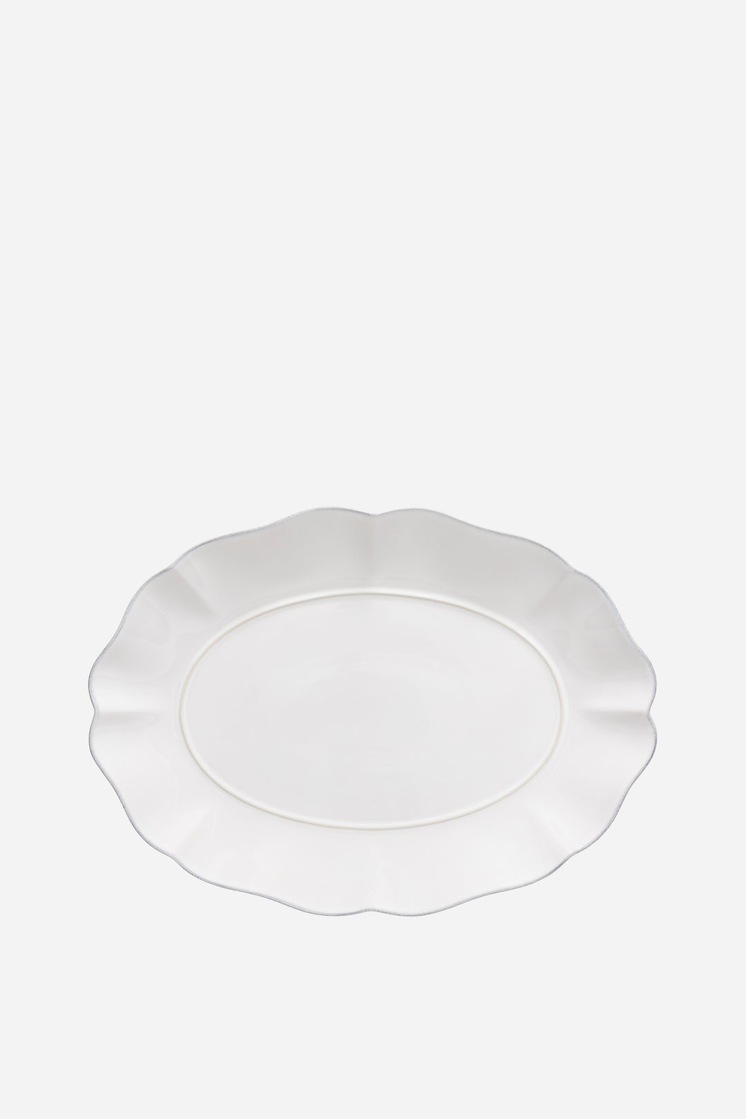White ceramic plate with scalloped edge on a white background