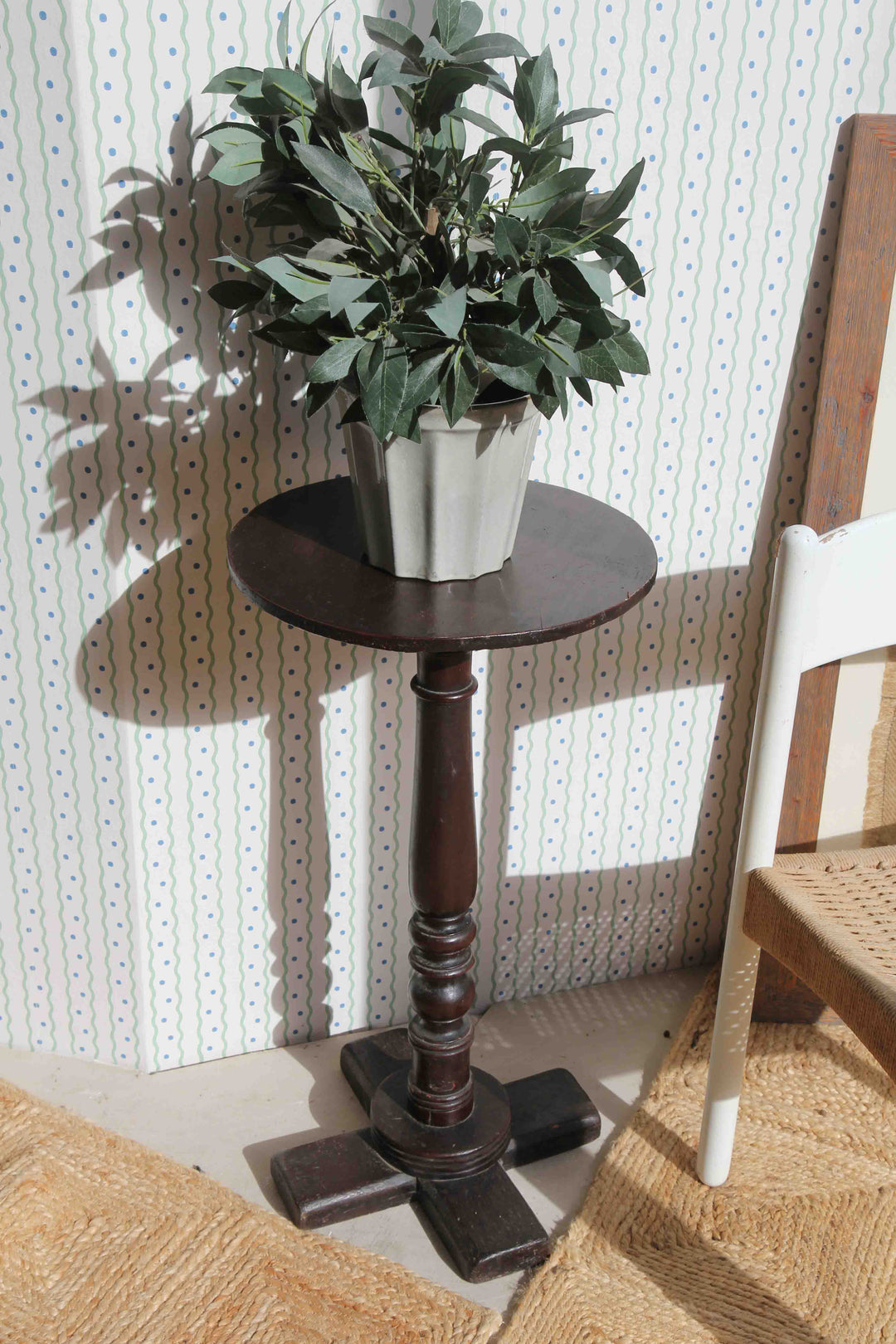 Small wooden table with a potted plant against a textured wall.