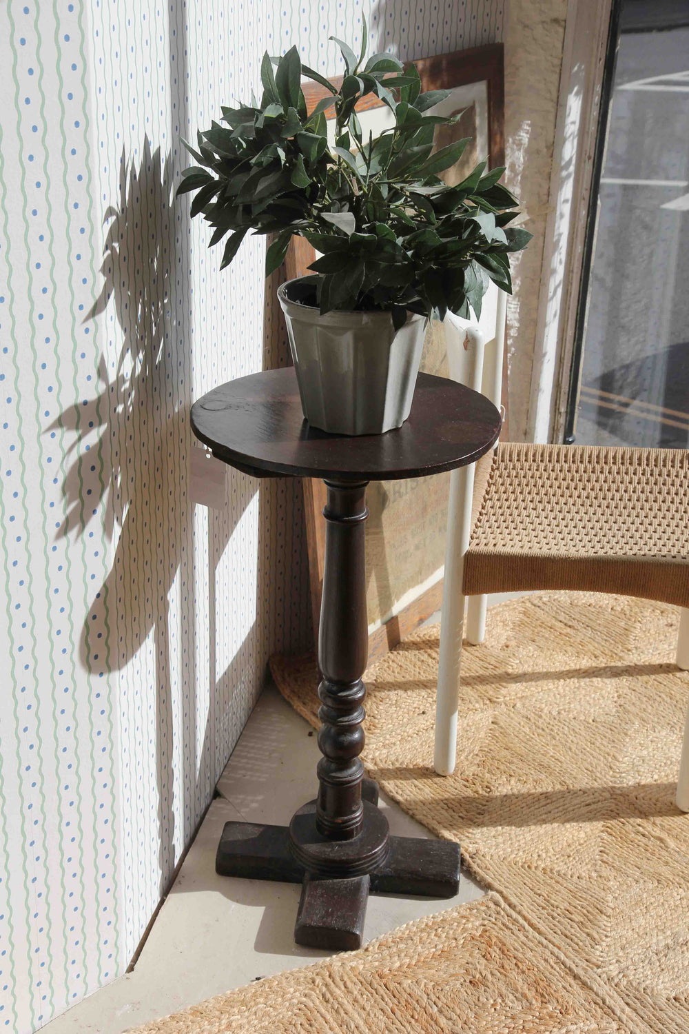 Small round wooden table with a plant on a patio