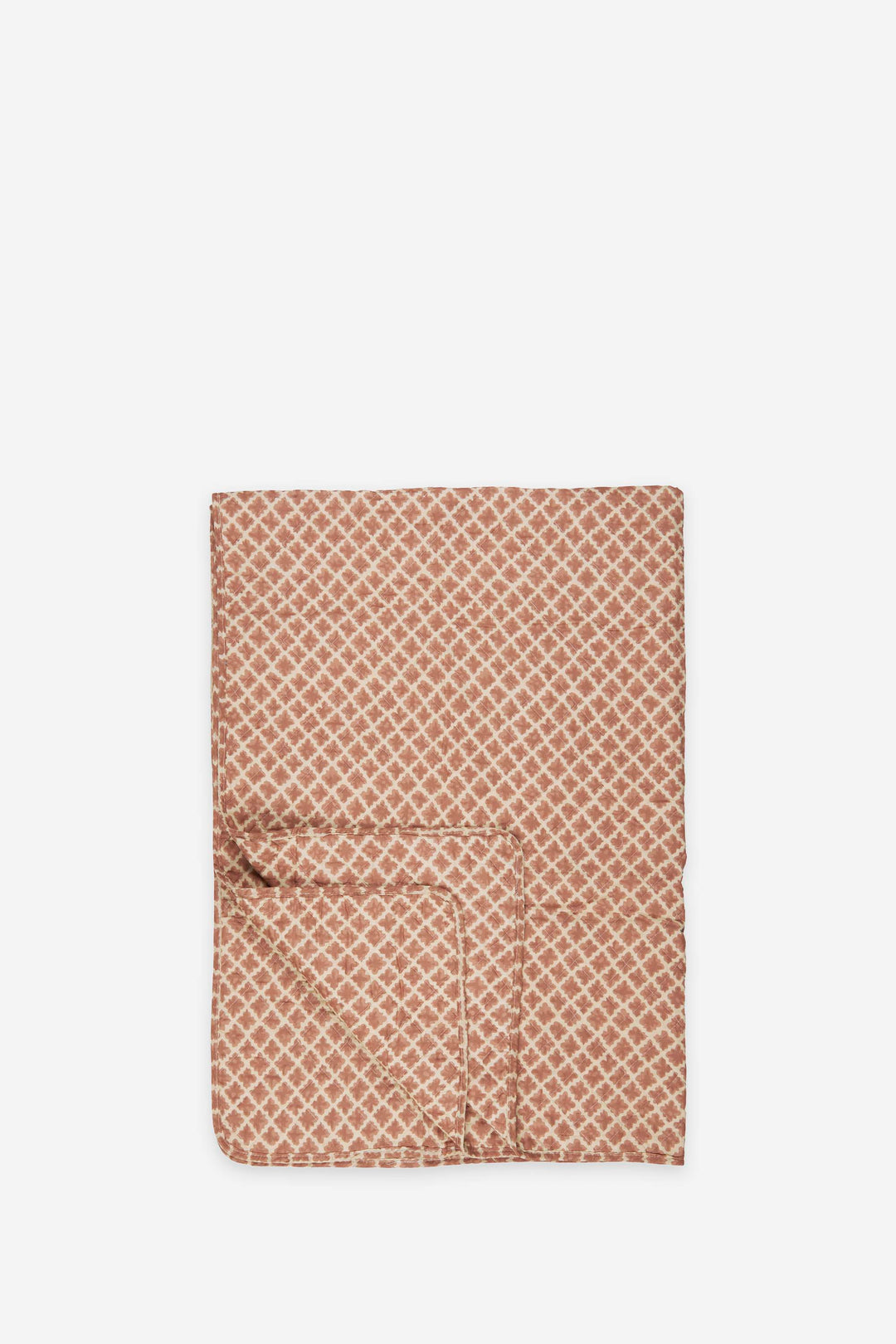 Folded quilt with a geometric rust pattern on a white background