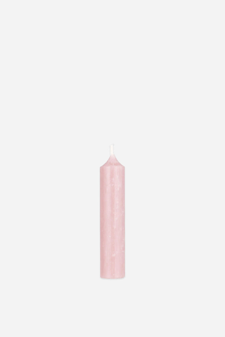 Single pink candle on a light pink background