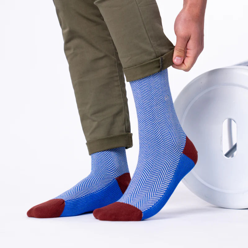 Person wearing blue and red patterned socks with beige pants on a white background