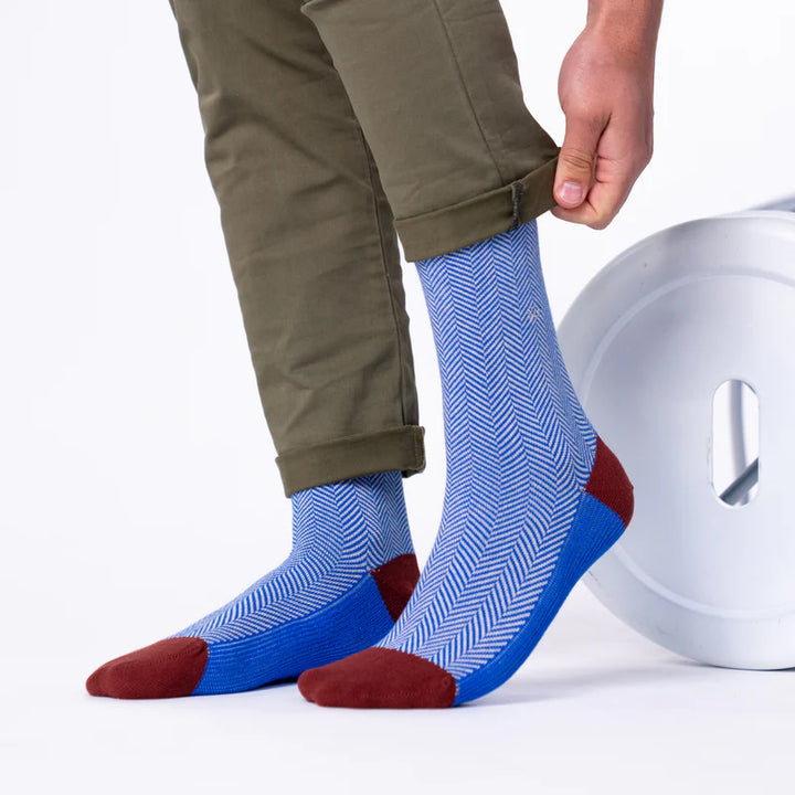Person wearing blue and red patterned socks with beige pants on a white background